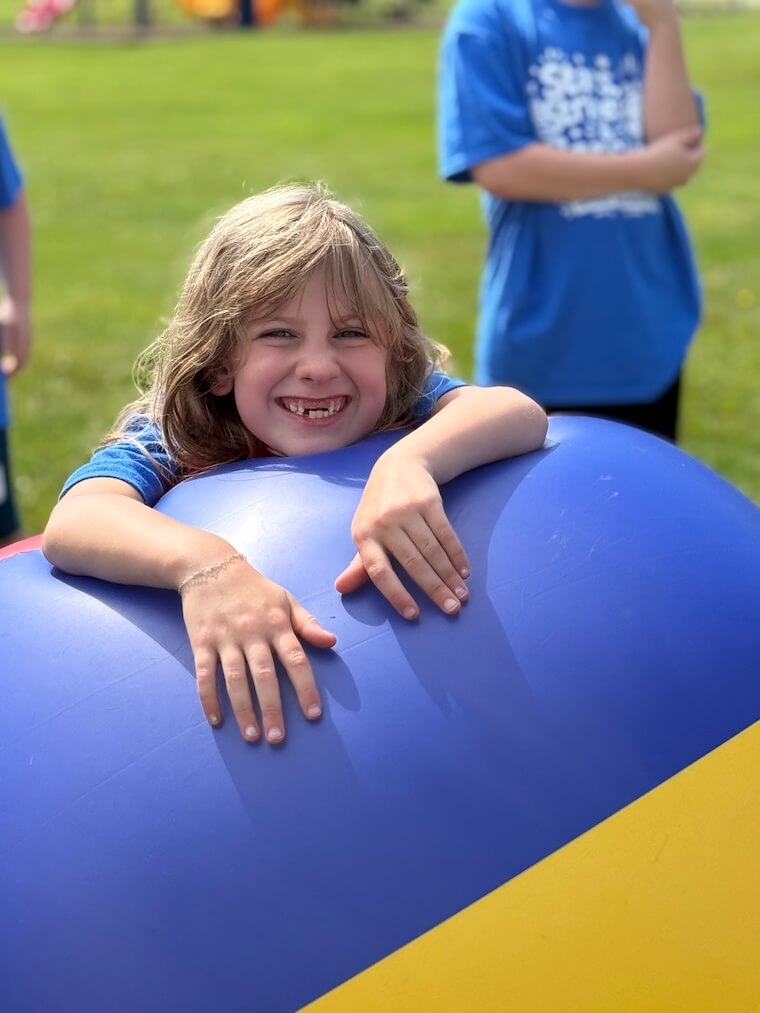 Smiling girl outside leaning on inflatable bounce house