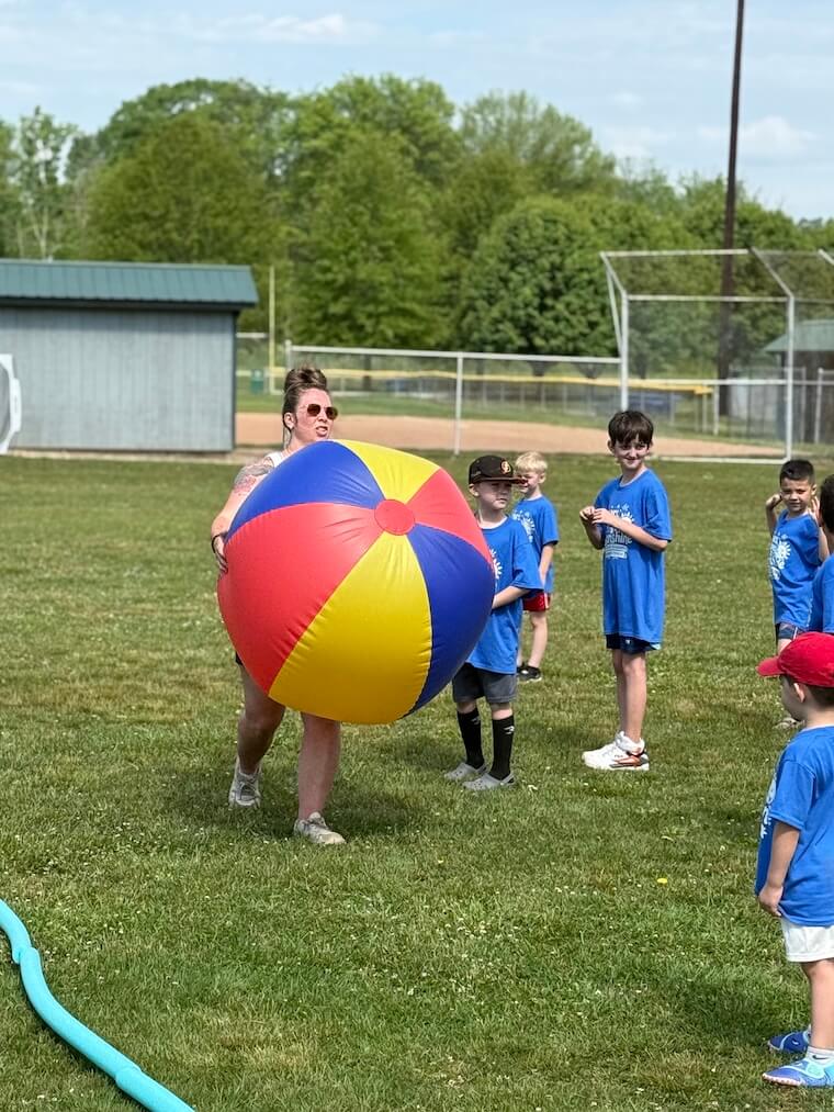 Teacher with beachball and students outside playing